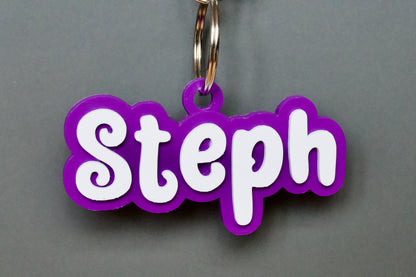 Purple keychain with 'Steph' in white on a grey background