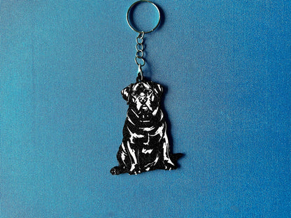 Rottweiler Silhouette Keyring laying on a blue table cloth. The keyring features a white background with a black silhouette of a Rottweiler.