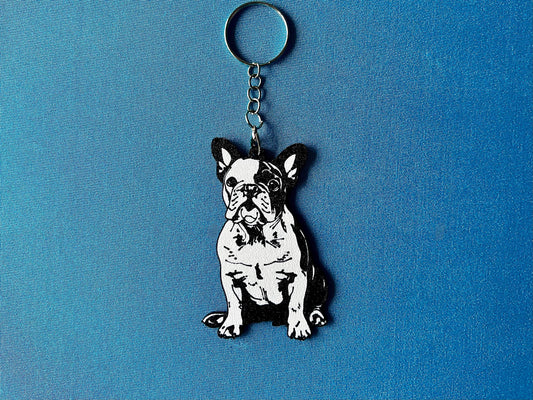 French Bulldog Silhouette Keyring laying on a blue table cloth. The keyring features a white background with a black silhouette of a French Bulldog.