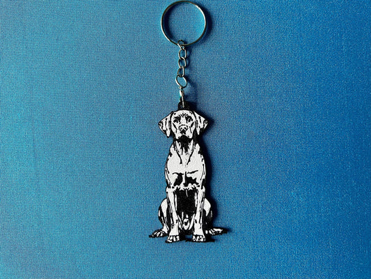 Hungarian Vizsla Silhouette Keyring laying on a blue table cloth. The keyring features a white background with a black silhouette of a Hungarian Vizsla.